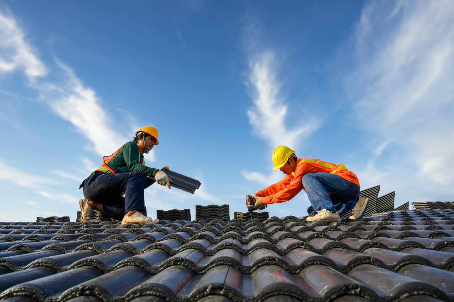 Two Summit Shield workers installing roof tiles under a blue sky