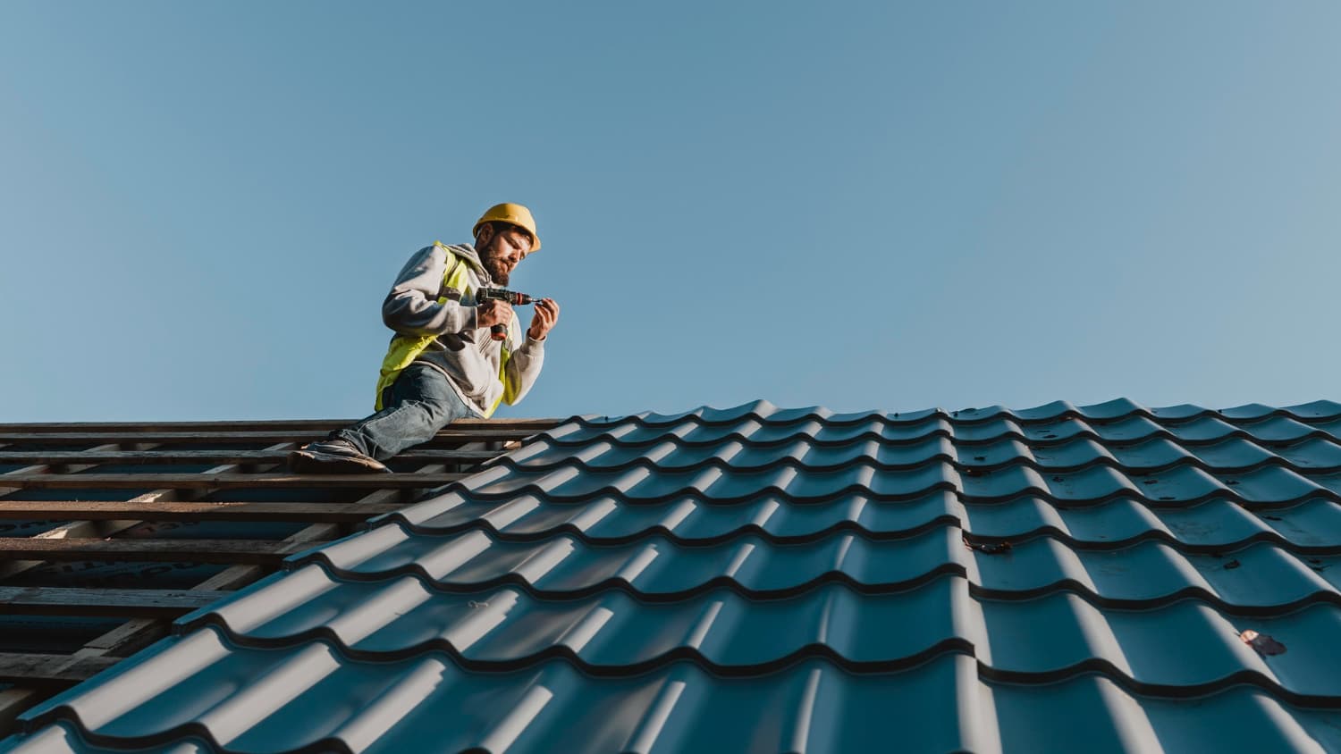 Summit Shield roofer working on a metal tile roof against a blue sky
